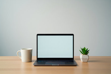 Clean modern workspace. Laptop and coffee cup. Small desk plant.の素材