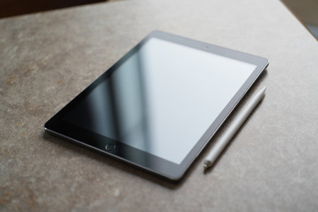 Sleek tablet and stylus pen on textured surface for digital art.の素材