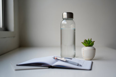 Workspace: Water bottle, succulent, and notebook. Hydration and productivityの素材