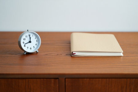 Alarm clock notebook wooden desk time management planning morning routine studyの素材