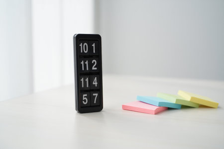Flip clock displaying numbers. Pastel sticky notes on white surface. Deadline reminder.の素材