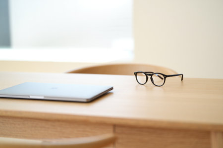 Laptop and spectacles on desk. Minimalist workspace for productivity.の素材