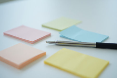 Close up of sticky notes. Pen on table surface. Clean background.の素材