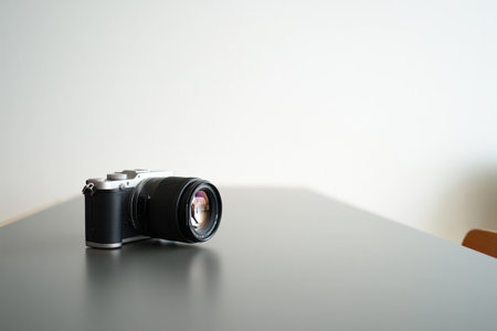 Silver and black mirrorless camera. Zoom lens on dark surface.の素材