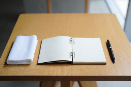 Open notebook with grid paper ready writing. White towel and pen creates workspace.の素材