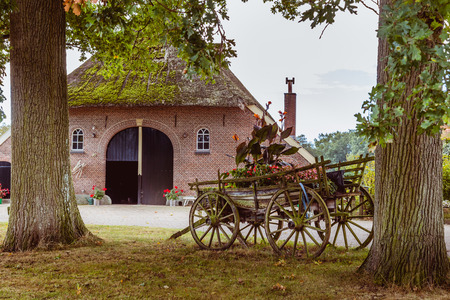 Old farmhouse with a woorden  chariot with flowers in frontの写真素材