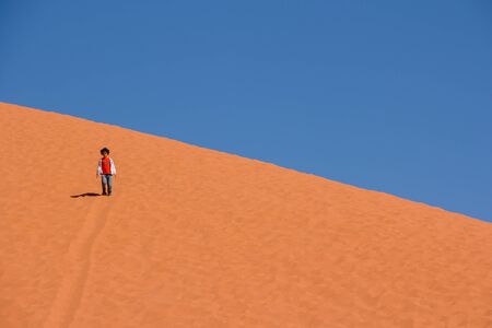 WADI RUM DESERT, JORDAN - APRIL 30, 2016: Little girl walking down from the highest sand dune in Wadi Rum desert in Jordan.のeditorial素材