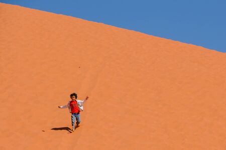 WADI RUM DESERT, JORDAN - APRIL 30, 2016: Little girl running down from the highest sand dune in Wadi Rum desert in Jordan.のeditorial素材