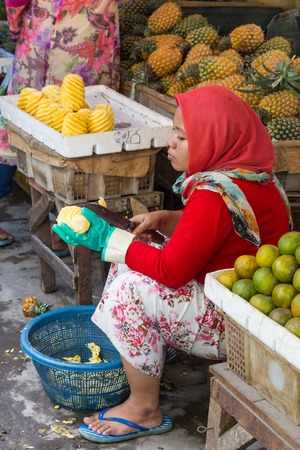Surabaya, Indonesia - November, 05, 2017: Woman cutting pineapple at the market in Surabaya in Indonesiaのeditorial素材