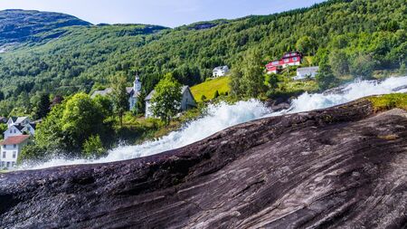 Panorama of small village Hellesylt with Hellesyltfossen waterfall in along Geiranger fjord in More og Romsdal county in Norwayの写真素材