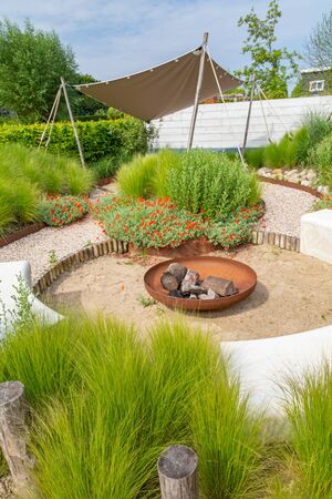 Garden design with sunshade, metal fireplace, marram grass and natural terrace inspired by the beach