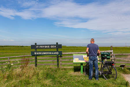 Workum, Netherlands - August 6, 2020: Male tourist reading information sign at entrance of nature...