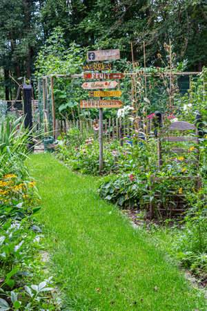 Barneveld, Netherlands- August 23, 2020: Cozy little garden with vegetables, colorful flowers,all kinds of decorations and signs with DUtch textのeditorial素材
