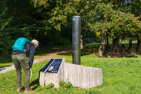 Borger, The Netherlands - October 16, 2022: Senior man reading information sign beside ground water measurement system in park in Borger Hondsrug in Drenthe The Netherlandsのeditorial素材