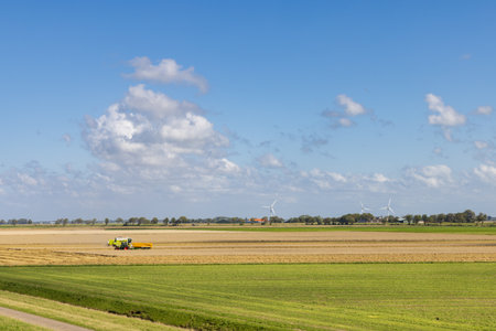 Agricultural fields with combine harvester near Pieterburen Het Hogeland in north Groningen in The Netherlandsの写真素材