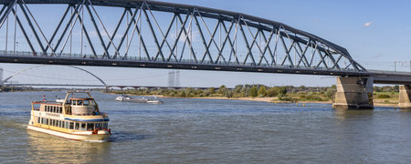 Nijmegen, The Netherlands - September 24, 2023: Cityscape of Nijmegen with scenic view of Pancake restaurant ship passing the bridge in river Waal on a sunny autumn day.のeditorial素材
