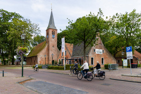 Roden, The Netherlands - August 29, 2023: Tourist passing picturesque church of Roden surrounded by oak trees, municipality Noordenveld in Drenthe The Netherlandsのeditorial素材