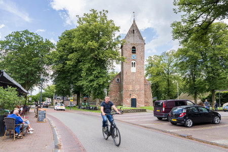 Norg, The Netherlands - July 7, 2024: Cyclist passing the monumental ancient churg in the center og village Norg in Municipality Noordenveld in the Netherlands. Traditional Esdorp in Northern Drenthe.のeditorial素材