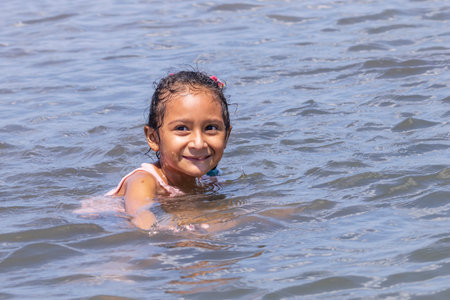 Las Penitas, Nicaragua - March 17, 2024: Young happy local girl having fun at the coast of Las Penitas entrance to Juan Venado island nature reserve in Nicaragua Central Americaのeditorial素材