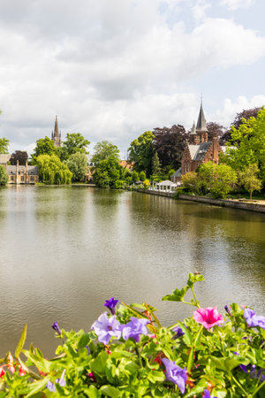 Minnewater lake and castle with colorful flowers in foreground in Brugge in Flanders Belgiumの写真素材