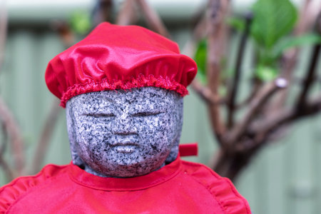 Closeup of small Buddha statue with red clothing at Saikoji temple in Yanaka subsurb in Tokyo, Japan.の写真素材