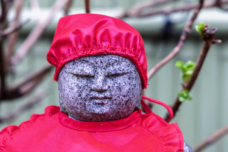Closeup of small Buddha statue with red clothing at Saikoji temple in Yanaka subsurb in Tokyo, Japan.の写真素材