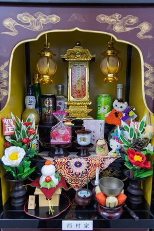 Nagasaki, Japan - March 22, 2025: Home altar called Butsudan with all kinds of relegiious elements, flowers and favorite food of deceased in buddha temple in Nagasaki in Japanのeditorial素材
