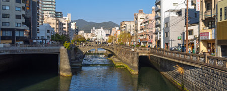 Nagasaki, Japan - March 22, 2025: People crossing famous Meganebashi bridge reflected in the Nakashima river in Nagasakin in Japanのeditorial素材