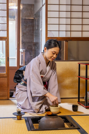 Kyoto, Japan: Japanese Woman in kimono demonstrating how to prepare trraditional matcha tea during a tea eremony in washitsu room with tatami mats and shoji sliding paper screens , Kyoto in Japan.のeditorial素材