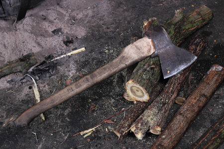 Old axe and firewood against a dark background.の写真素材