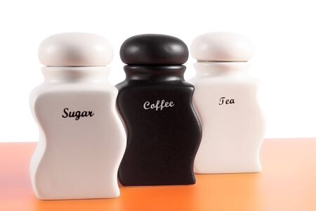 Capacities for sugar, coffee, tea on an orange surface and a white background.