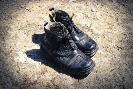 The thrown old winter boots on an earth backgroundの写真素材