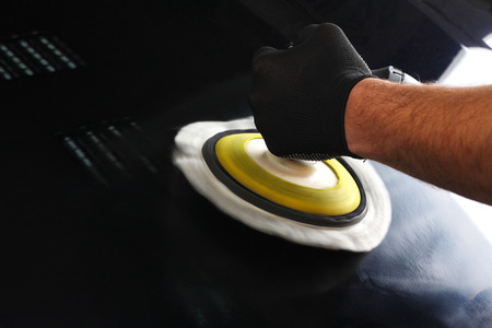 The worker polishes a car cowl with the electric tool. Close up.の写真素材