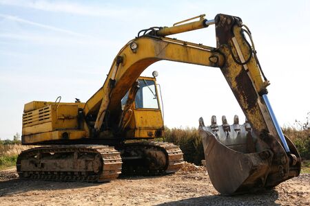 The old yellow caterpillar excavator thrown into a field.