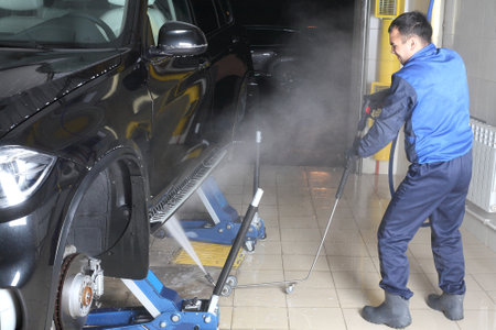 MOSCOW, RUSSIA - OCTOBER 4, 2015: The worker washing of the car under a high pressure. Car service.のeditorial素材