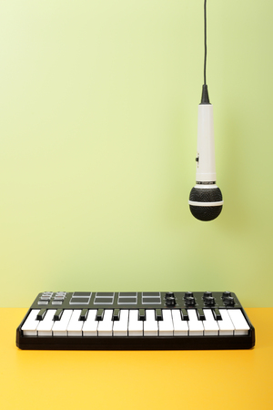 Musical instrument - MIDI keyboard and vokal microphone for a karaoke hangs down on top on a flavovirent background.の写真素材