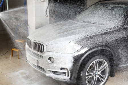 MOSCOW, RUSSIA - OCTOBER 4, 2015: The worker washing of the car under a high pressure. Car service.のeditorial素材