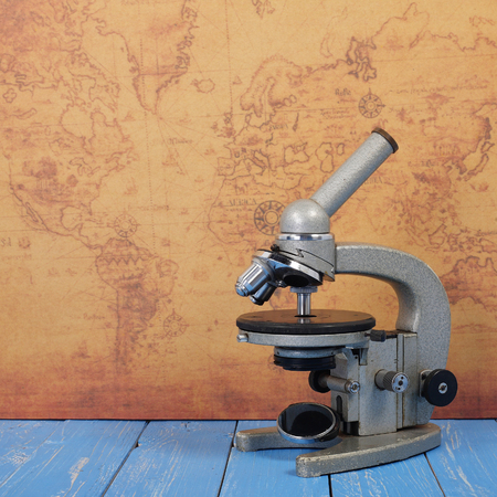 Science and education - Retro microscope world map and blue wooden plank background