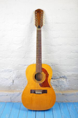 Musical instrument - Front view vintage twelve-string acoustic guitar on a brick background and blue...