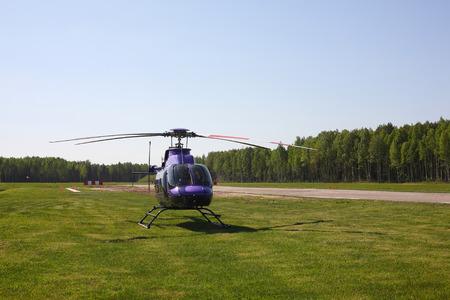 Aircraft - Purple helicopter on the parking against the wood and sky.の写真素材