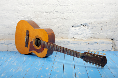 Musical instrument - Vintage twelve-string acoustic guitar on a brick background and blue wooden...