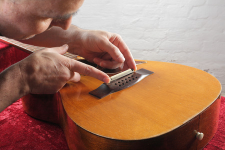 Musical instrument guitar repair and service - Grinding bridge nut.の写真素材