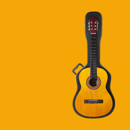 Musical instrument - Acoustic classic guitar from above on a hard case on a yellow background.