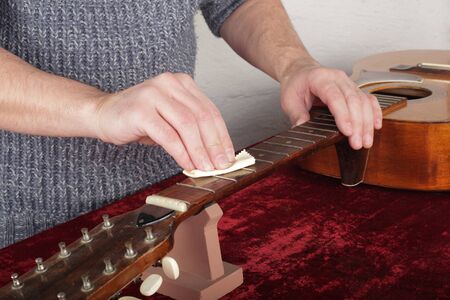 Musical instrument guitar repair and service - Worker moistening and impregnation of an fingerboard neck special oil.の写真素材