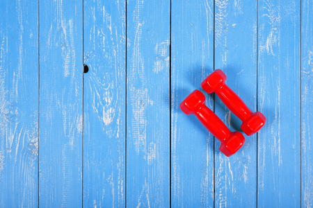 Sport and fitness - Two red dumbbell on a blue wooden plank background.の写真素材