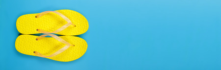 Clothes, shoes and accessories - top view yellow pair flip-flops sandal on a blue backgroundの写真素材