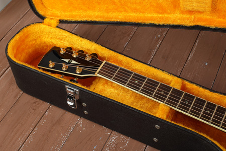 Musical instrument - Fragment neck brown cutaway acoustic guitar in hard case on a wood background.の写真素材