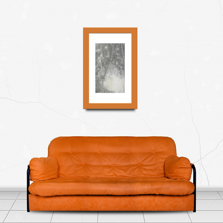 Upholstered furniture in Home interior - Orange modern divan sofa made of cloth in front and Painting picture in a frame of white wall backgroundの写真素材