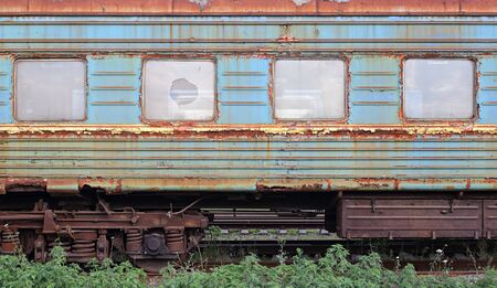 Transport - Side view on the railway old rusty thrown car with the broken windows.