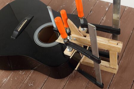 Guitar repair and service - Repair clamping broken sound board acoustic guitar wooden background